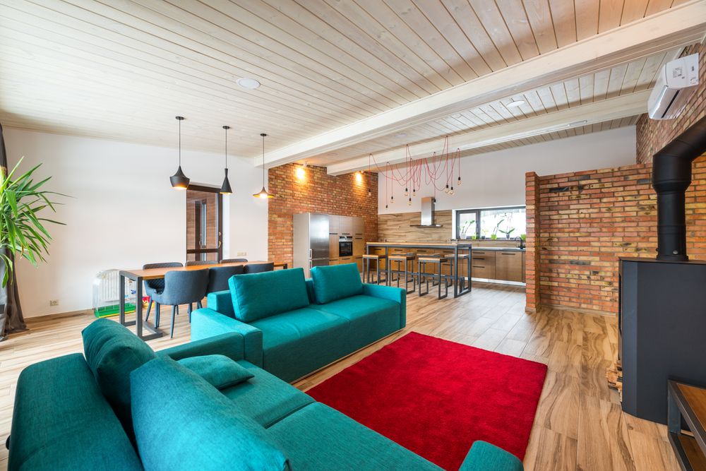 Stock photo: loft living room with teal sofas, a red rug and a wood ceiling