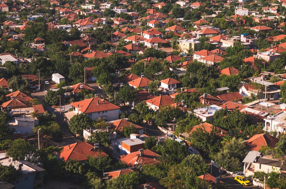 Aerial view of a neighbourhood of red-tiled roofs among green trees
